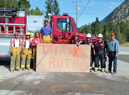 Members of the Canal Flats Fire Department hold up a sign to thank Ruth Copeland-Brunell for her work in helping to bring the fire truck to the village.